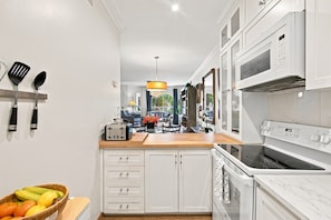 A modern kitchen with white cabinetry, a wooden countertop, a toaster, and a microwave.