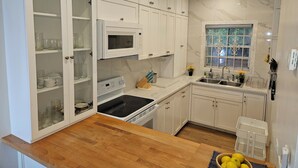 Une cuisine avec des meubles blancs, un four à micro-ondes, une cuisinière et un évier.