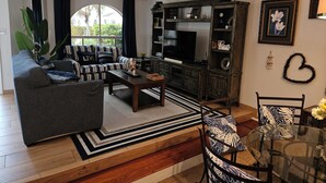 Un salon avec un canapé, une table basse, un téléviseur et une bibliothèque.
