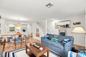 A modern living room with a grey sofa, wooden coffee table, and a staircase leading to another level.