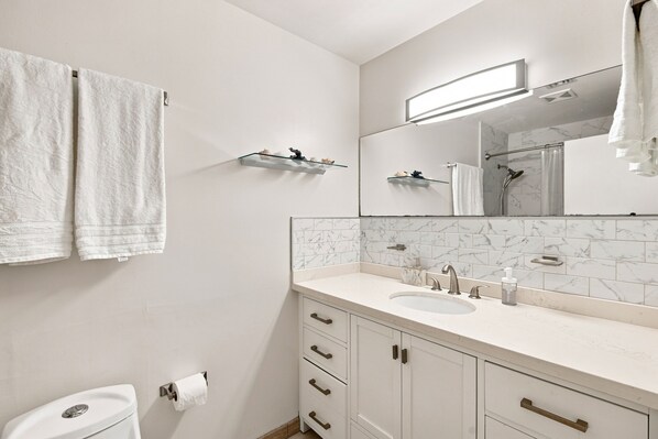 A modern bathroom with a white sink, mirror, and two towels hanging on the wall.