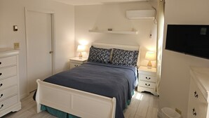 Une chambre à coucher avec un lit, des tables de chevet, un téléviseur et un ventilateur de plafond.