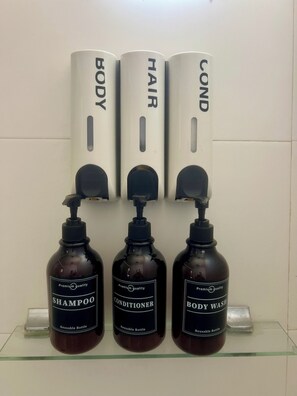 Tres botellas de champú, acondicionador y gel de baño sobre una estantería.