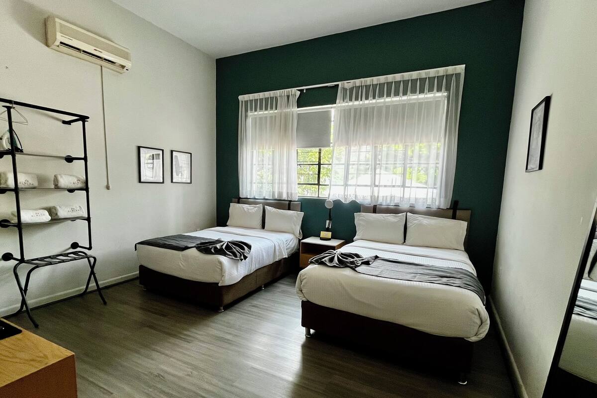 Habitació d'hotel amb dos llits, un armari, una taula de nit i una finestra amb cortines.