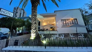 A modern hotel with a palm tree, outdoor seating, and a sign indicating its presence. - Jazz & Stay (Guadalajara)