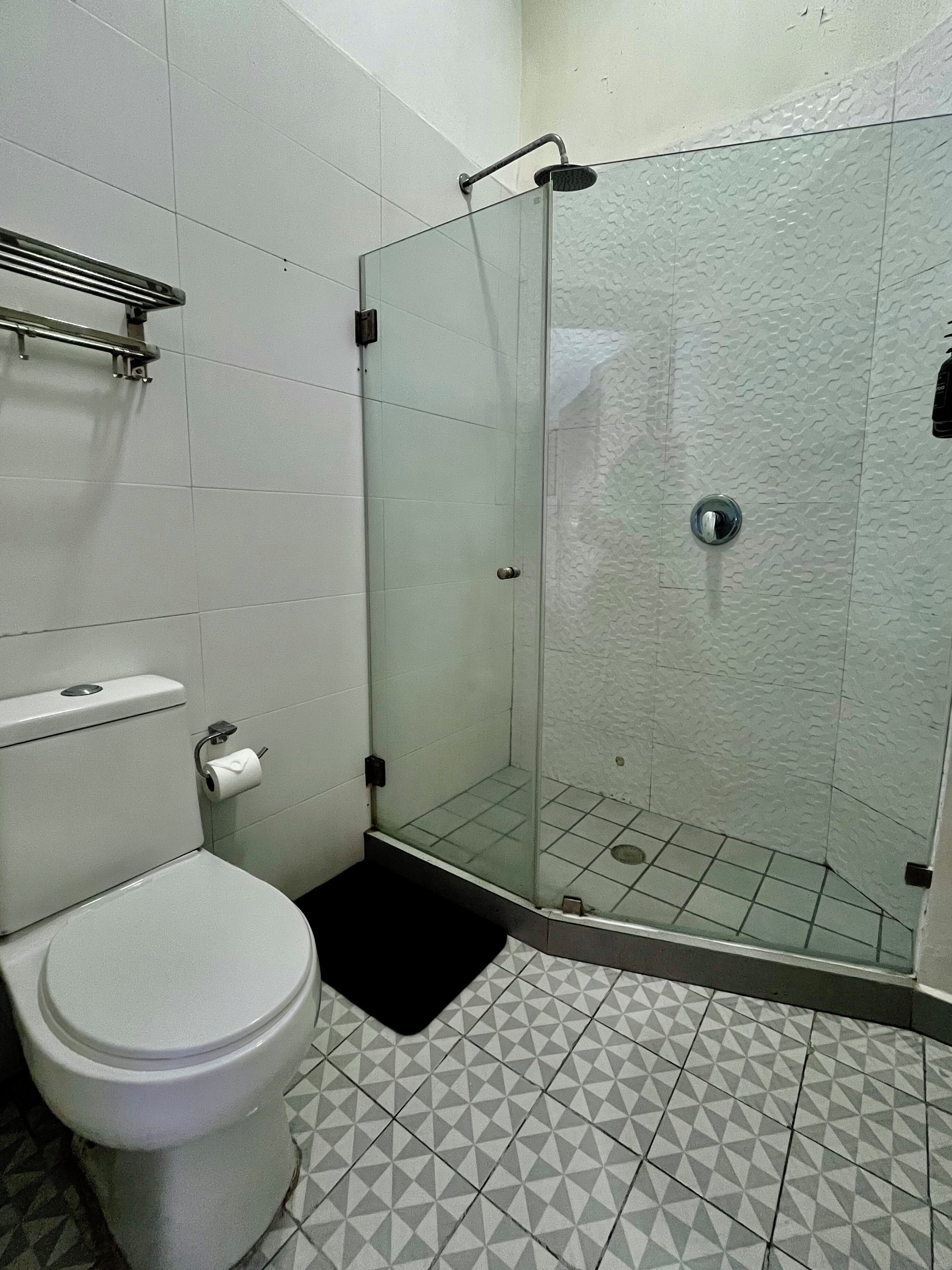 Ein Badezimmer mit Toilette, einer Duschkabine und fliesenbelagtem Boden.