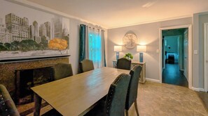 A dining area with a table, chairs, a cityscape painting, a globe, and a lamp.