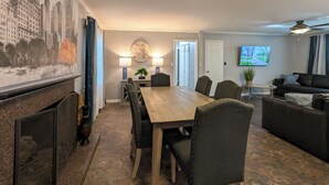 Een eetruimte met een houten tafel en stoelen, een bijzettafeltje met een lamp, en een decoratieve wereldbol aan de muur.