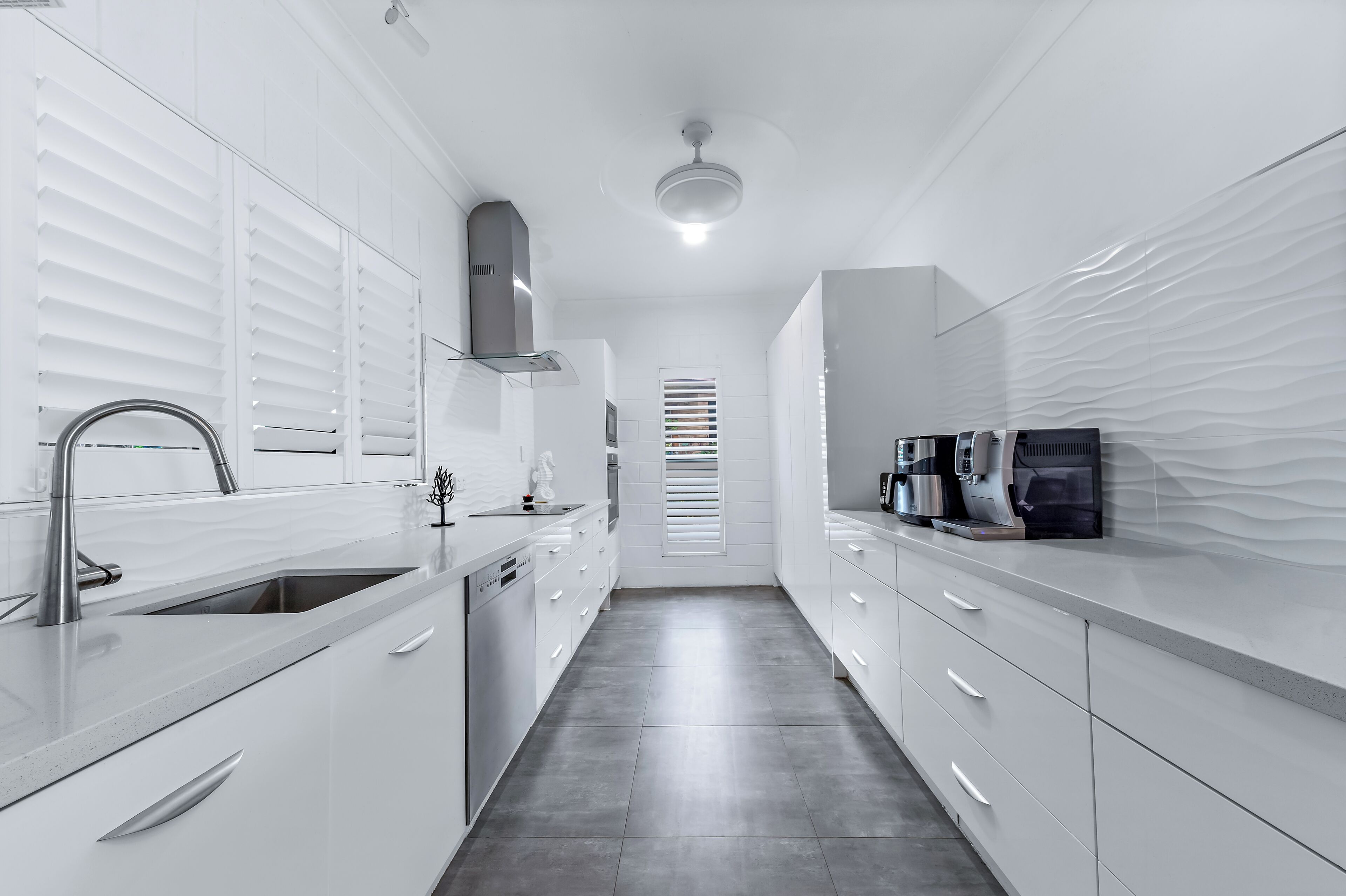 A modern kitchen with white cabinetry, stainless steel appliances, and a sleek design.