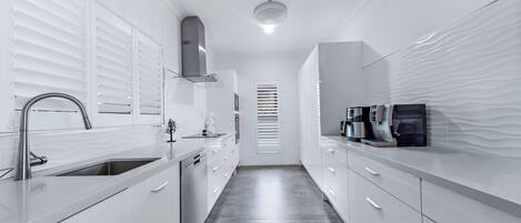 A modern kitchen with white cabinetry, stainless steel appliances, and a sleek design.