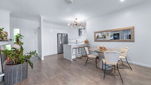 Una cocina moderna con una isla central, armarios blancos y una araña.