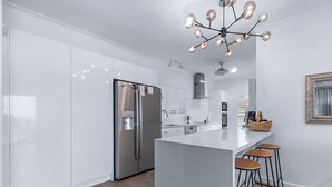 Una cocina moderna con electrodomésticos de acero inoxidable, una isla central con taburetes y un candelabro decorativo.