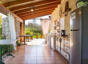 A kitchen with a stone wall, wooden ceiling, tiled floor, and a refrigerator. - Charming country house with private pool near Muro (MURO)