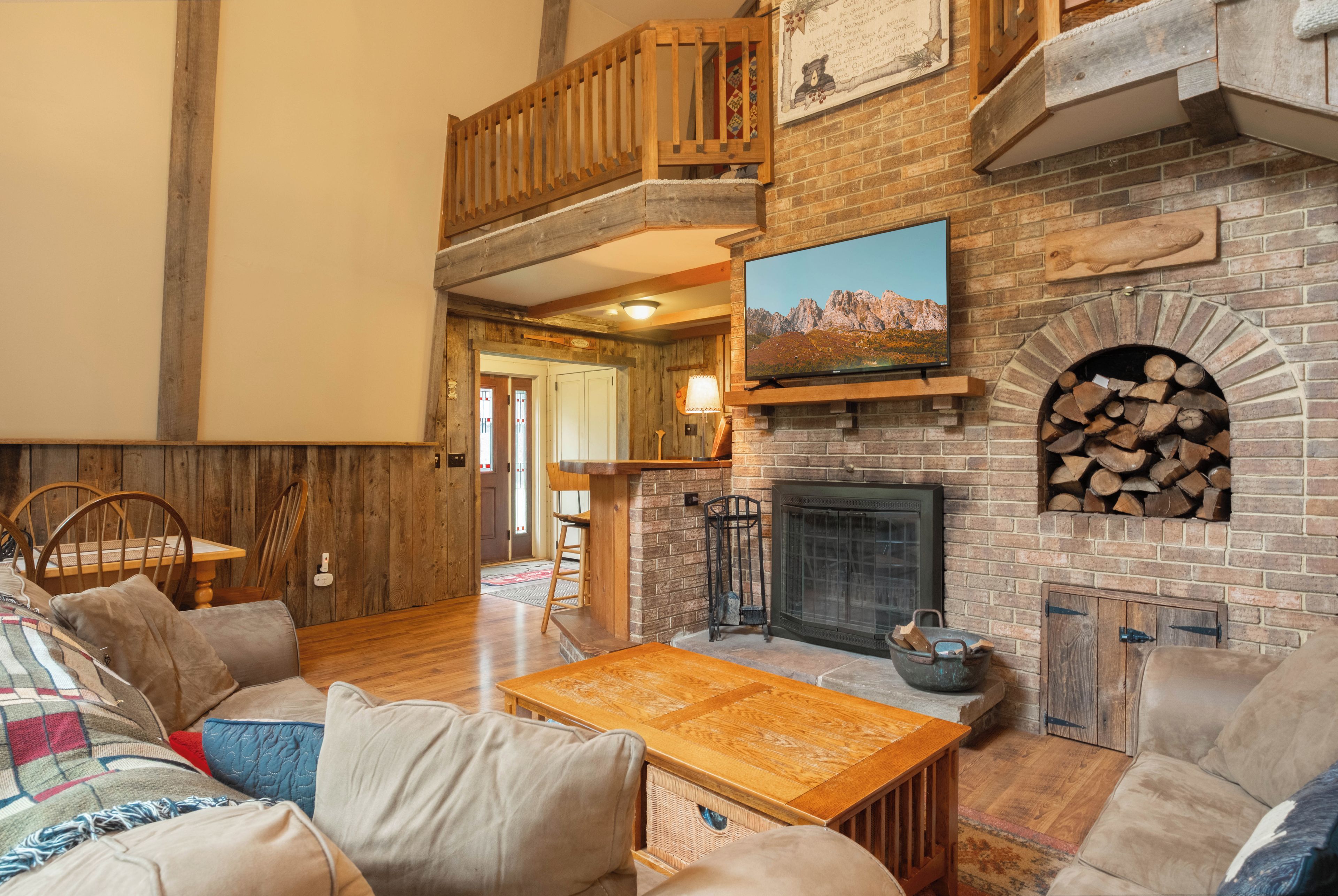 A cozy living room with a fireplace, a television mounted above it, and a comfortable seating area with a sofa and a coffee table.