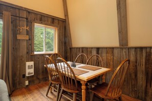 A wooden dining area with a table and chairs, a window, and a wall-mounted heater. - Boulder Retreat | 2BR/2BA Accident w/ Hot Tub (Accident)