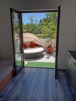 A room with a sliding glass door leading to an outdoor seating area with a round table and a potted plant. - Holiday apartment with terrace (Krk)