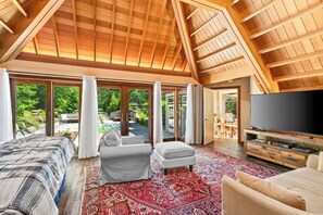 A spacious bedroom with a large bed, a TV, and a view of a garden through sliding glass doors. - Charlestown Retreat | 2 Reflection Pools and Fire Pits (Charlestown)