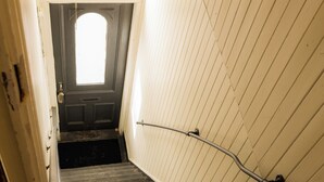Eine schmale Treppe mit Handlauf, eine Tür am oberen Ende und ein Oberlicht darüber.