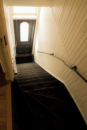 A narrow stairway with a handrail, a door at the top, and a skylight above. - Urban Oasis (Québec)