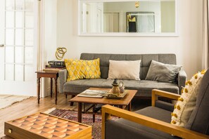 A living room with a sofa, armchair, coffee table, and a chessboard. - Urban Oasis (Québec)