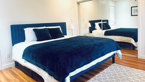 Una camera da letto con un letto, un comodino, uno specchio e un pavimento in legno.