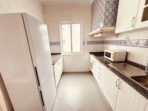 A kitchen with white cabinets, a microwave, a toaster, and a window. - Spacious Porto Escape – Vale Formoso (Porto)
