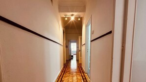 Un passadís amb un paviment de punt rombe, parets blanques i una porta al final.