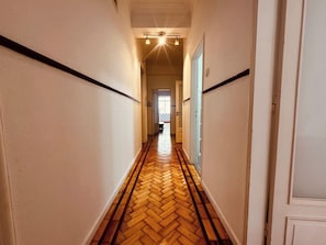 A hallway with a herringbone floor, white walls, and a door at the end. - Spacious Porto Escape – Vale Formoso (Porto)