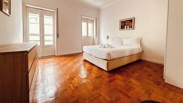Un dormitori amb un llit, un armari i una porta que dona a una altra habitació.