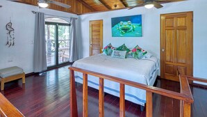 A bedroom with a bed, wooden ceiling, ceiling fans, a door, and a window.