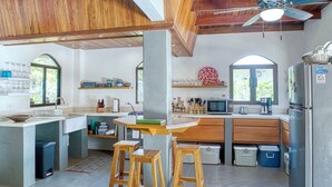 A kitchen with wooden stools, a refrigerator, a microwave, and a sink.