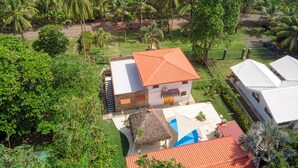 A coastal property with a white building, a thatched-roof structure, and a blue swimming pool.