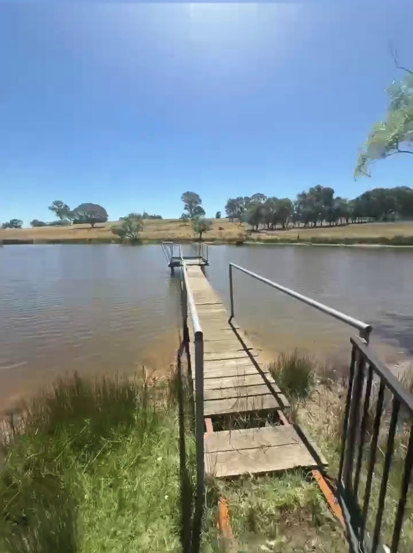 Une jetée en bois s’étendant sur un lac paisible, sous un ciel dégagé.