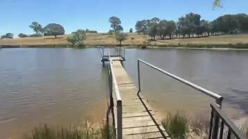 Une jetée en bois s’étendant sur un lac paisible, sous un ciel dégagé.