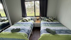 A bedroom with two beds, a ceiling fan, a nightstand, and a window with curtains.