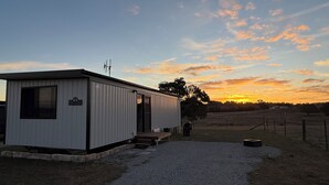 A single-story building with a gravel driveway leading to a wooden bench.