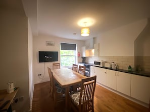 A compact kitchen with a dining table, chairs, a TV, and a window. - Luxury Riverside London Apartment (London)