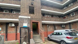 Un edificio a più piani in mattoni con una scala centrale, un'auto parcheggiata di fronte e un cartello che indica 'Ellington House'.