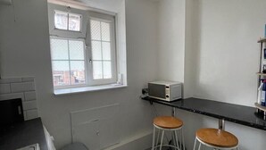 Une petite cuisine équipée d’une fenêtre, d’un four à micro-ondes, de deux tabourets et d’un évier.