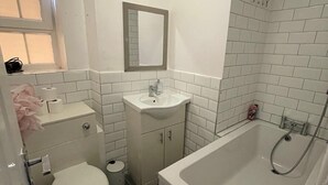 Une salle de bain comprenant des toilettes, un lavabo, un miroir et une baignoire.