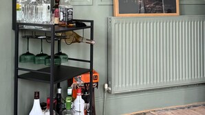 Une pièce avec un mur recouvert de miroirs, un radiateur, un plancher en bois et une étagère contenant diverses bouteilles et verres.