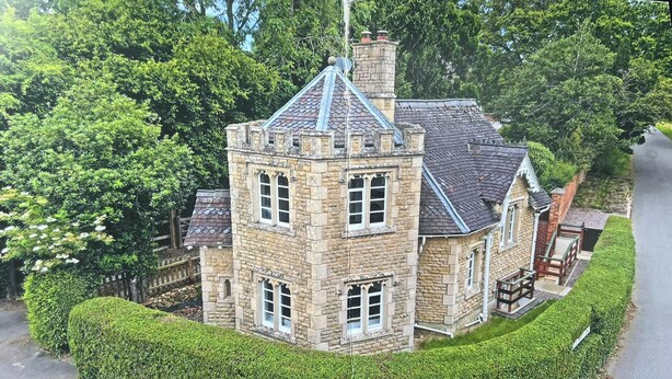 Une maison en pierre dotée d’une tourelle, de nombreuses fenêtres et d’une cheminée.