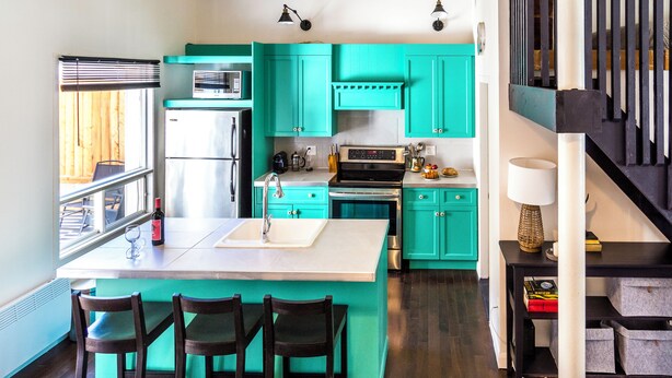 A kitchen with teal cabinets, a stainless steel refrigerator, a sink, and a stove. - The blacksmith's shop - L'atelier de forgeron (Québec)