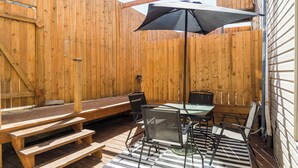 A wooden deck with a table, chairs, and a bench. - The blacksmith's shop - L'atelier de forgeron (Québec)