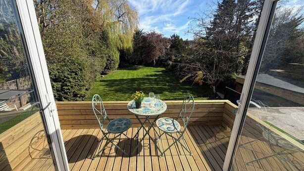 An outdoor deck with a table and chairs, surrounded by a well-maintained garden and trees. - 1 Bed - Sleeps 3 - Parking - Pets (London)