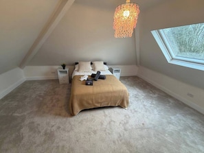 Een slaapkamer met een bed, nachtkastjes, een lamp en een raam.