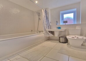 Ein modernes Badezimmer mit Badewanne, Dusche, Toilette und Waschbecken.