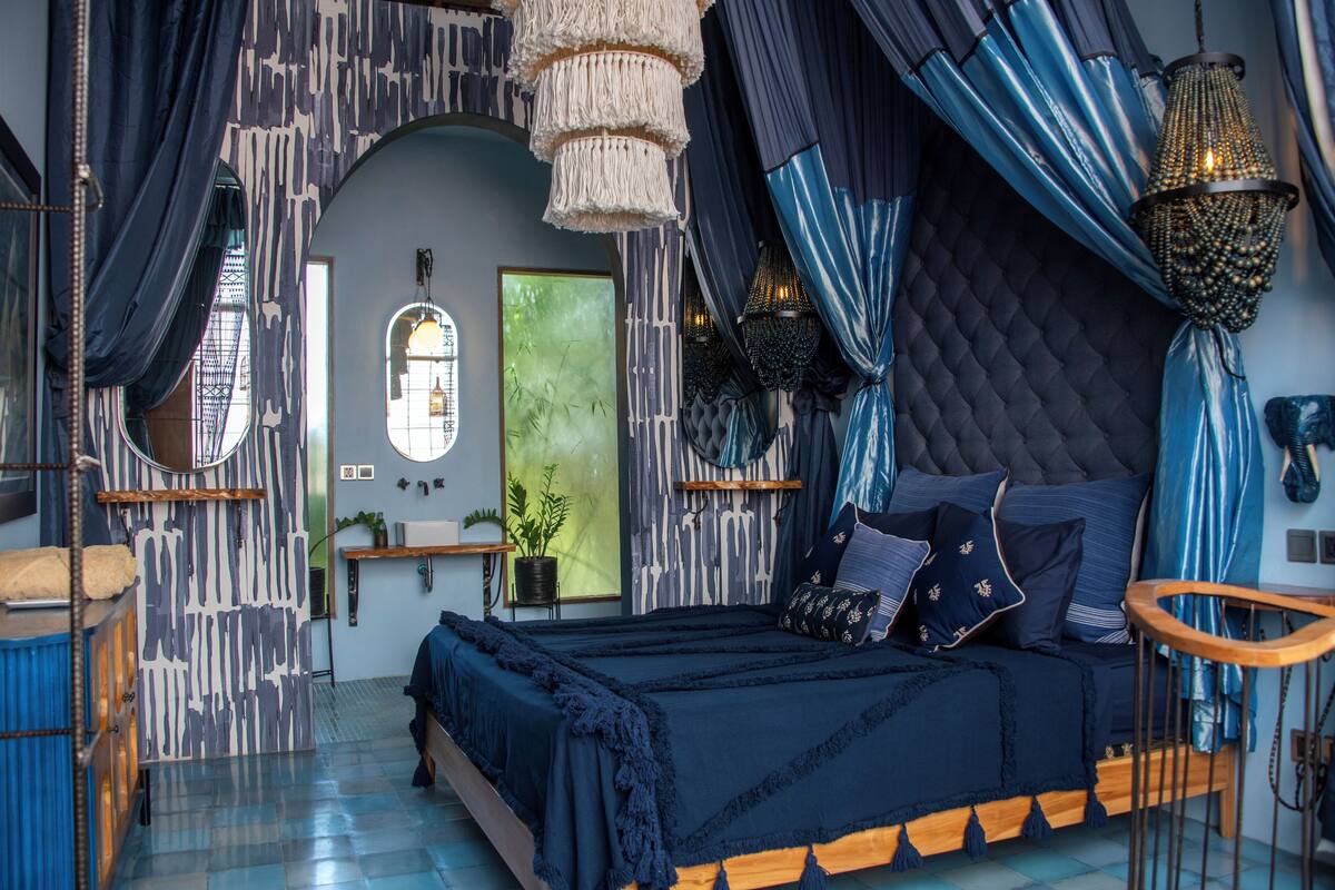 A bedroom with a large bed, a window, and a chandelier.