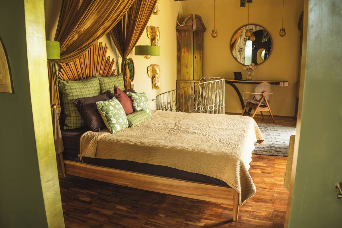 A bedroom with a bed, a chair, a mirror, and a cabinet.