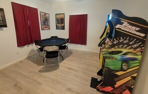 Ein Zimmer mit einem Esstisch, roten Vorhängen, Postern an der Wand und einer Wanddekoration zum Thema Auto.